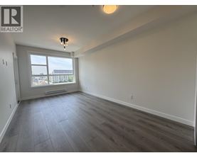 A spacious room with a large window and wooden flooring.
