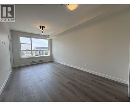 A spacious room with a large window and wooden flooring.