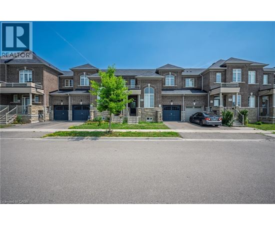 A large, multi-family home with a car parked in front.