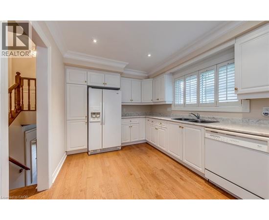 A well-lit, spacious kitchen with white cabinets and wooden flooring.