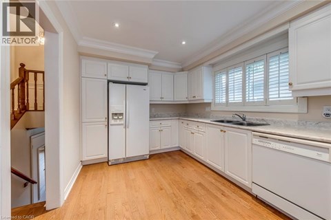 A well-lit, spacious kitchen with white cabinets and wooden flooring.