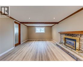 A spacious room with a fireplace and wooden flooring.