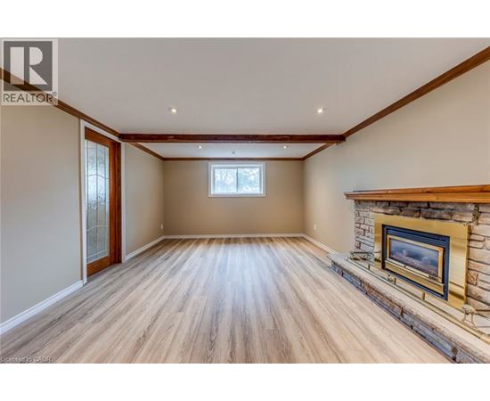 A spacious room with a fireplace and wooden flooring.