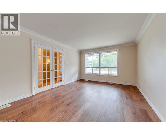 A room with wooden floors and a window with a view of trees outside.