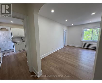 A real estate listing photo of a room with wood floors and white walls.