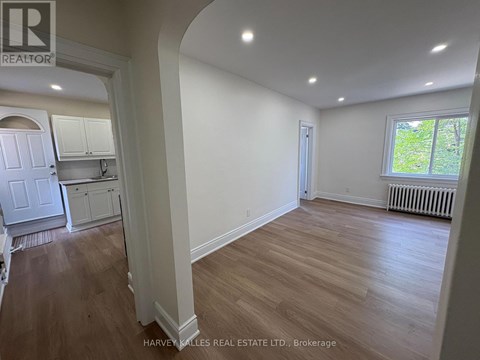 A real estate listing photo of a room with wood floors and white walls.