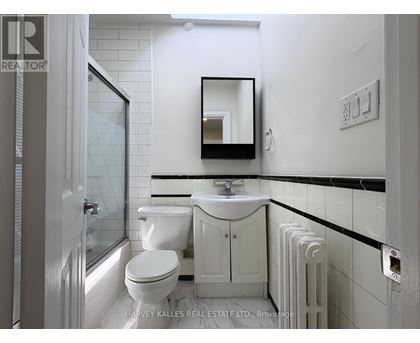 A white bathroom with a toilet, sink, and mirror.
