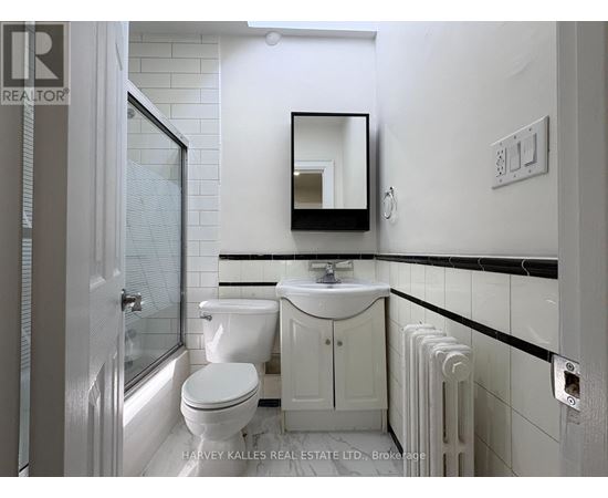 A white bathroom with a toilet, sink, and mirror.