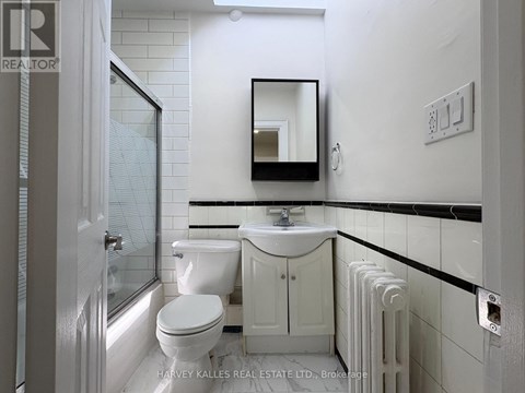 A white bathroom with a toilet, sink, and mirror.