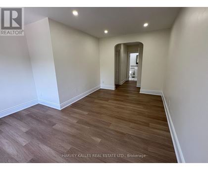 A spacious room with wooden flooring and white walls.