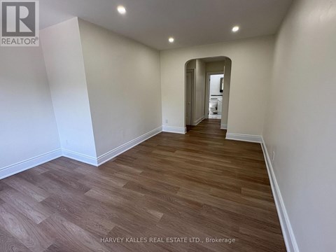 A spacious room with wooden flooring and white walls.