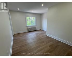 A room with wooden flooring and a window with a white frame.