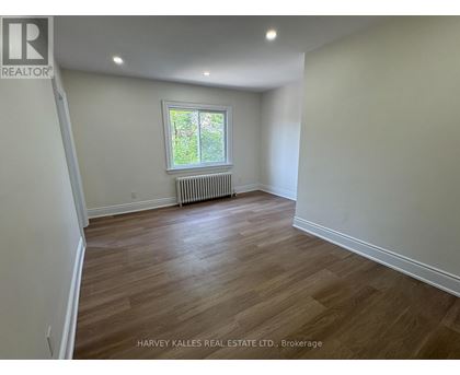 A room with wooden flooring and a window with a white frame.