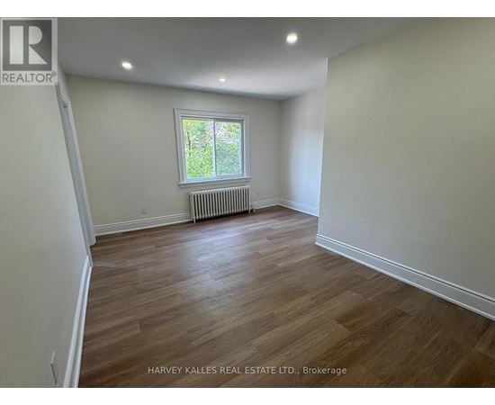 A room with wooden flooring and a window with a white frame.