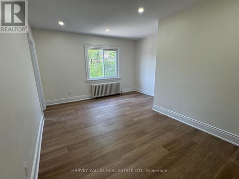 A room with wooden flooring and a window with a white frame.