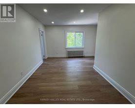 A room with wooden flooring and a window with a view of trees outside.