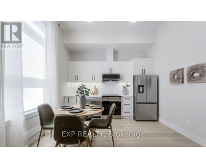 A dining area with a table set for four and a kitchen in the background.
