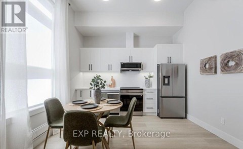 A dining area with a table set for four and a kitchen in the background.
