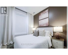 A bedroom with a large bed, a nightstand with a lamp, and a painting on the wall.