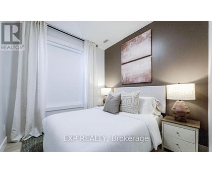 A bedroom with a large bed, a nightstand with a lamp, and a painting on the wall.