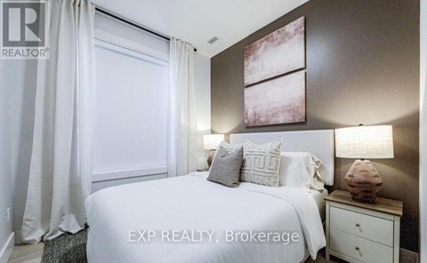 A bedroom with a large bed, a nightstand with a lamp, and a painting on the wall.