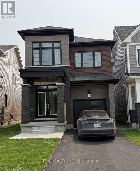 A grey car is parked in front of a house with a sign that says "TEN REALTOR INC. Brokerage".