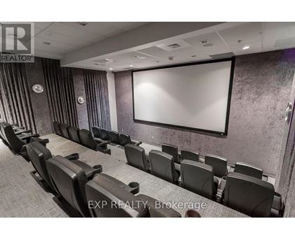 A row of black chairs are arranged in front of a white screen.
