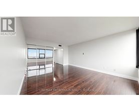 A spacious room with wooden flooring and a large window.