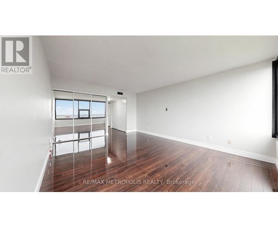 A spacious room with wooden flooring and a large window.