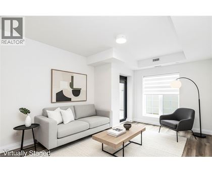 A living room with a grey couch, a black chair, a wooden coffee table, and a painting on the wall.