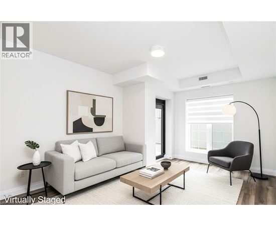 A living room with a grey couch, a black chair, a wooden coffee table, and a painting on the wall.