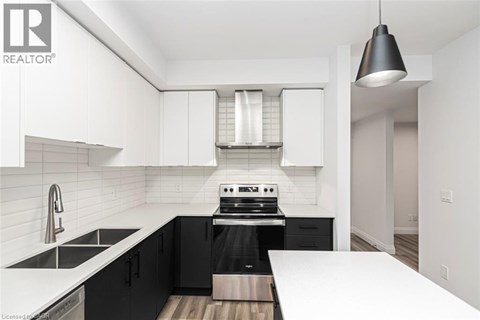 A modern kitchen with black cabinets and white countertops.