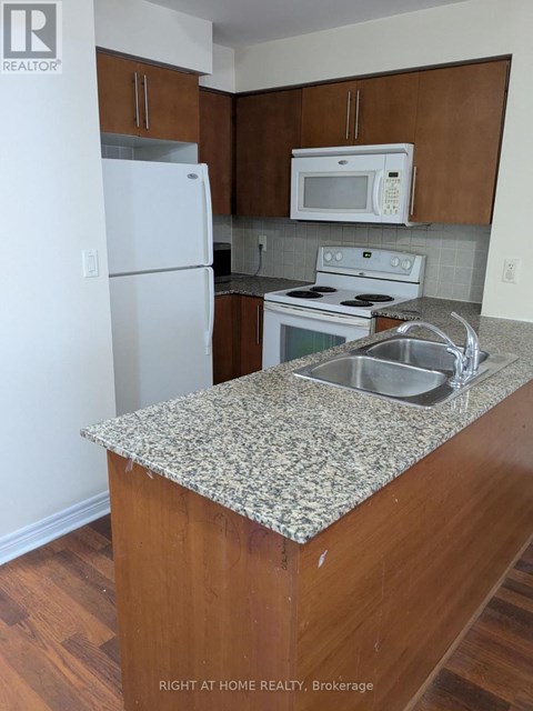 A kitchen with a granite counter top and a white fridge.