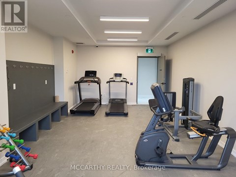A gym room with treadmills, exercise bikes, and a bench.