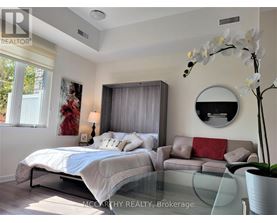 A bedroom with a bed, a couch, and a round mirror on the wall.