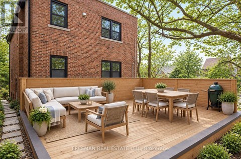 A wooden deck with a table and chairs is in front of a brick building.