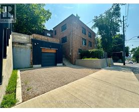 A building with a brick facade and a garage door is for sale.