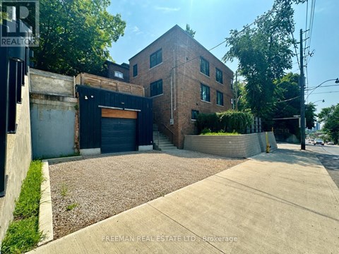 A building with a brick facade and a garage door is for sale.
