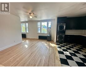 A room with wooden flooring and a black and white checkered floor mat.