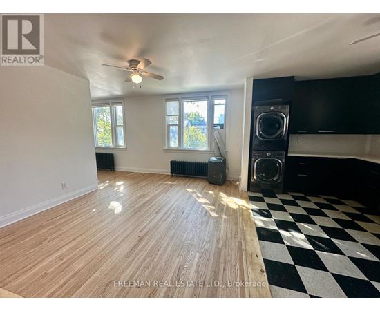 A room with wooden flooring and a black and white checkered floor mat.