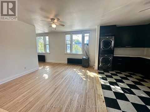 A room with wooden flooring and a black and white checkered floor mat.