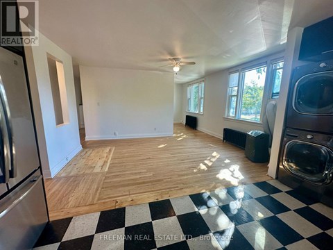 A large empty room with wooden flooring and a checkered floor.