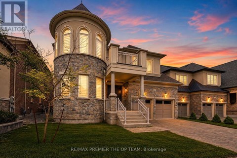 A large, beautiful house with a stone tower and a garage is shown.