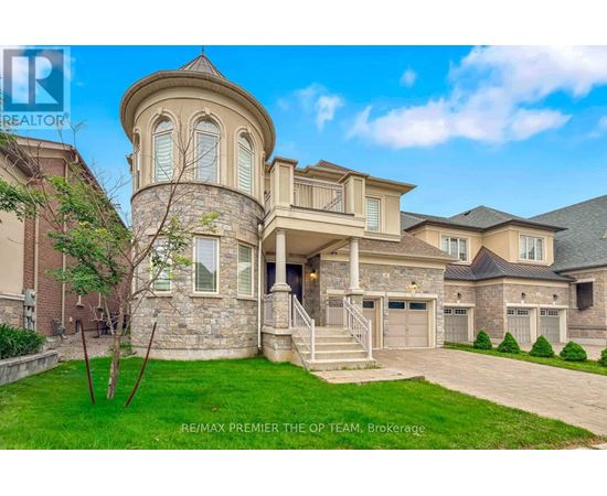 A large, luxurious house with a stone tower and a well-manicured lawn.