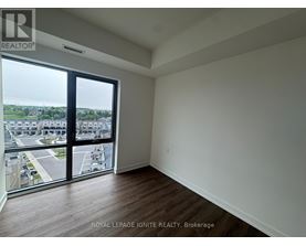 A room with a view of a parking lot and buildings outside.