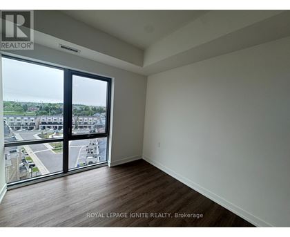 A room with a view of a parking lot and buildings outside.