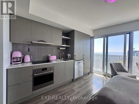 A kitchen with grey cabinets and a large window overlooking the ocean.