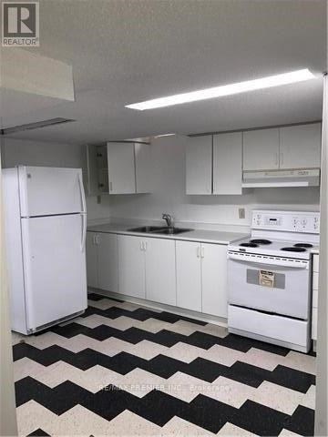 A black and white checkered floor in a kitchen with white appliances.