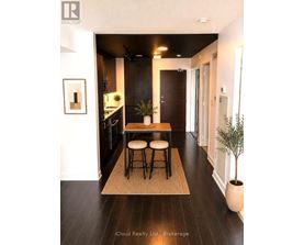 A modern kitchen with dark wood floors and a small island with two stools.