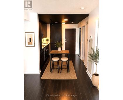 A modern kitchen with dark wood floors and a small island with two stools.
